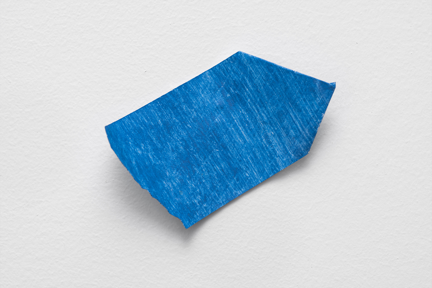 on a white background, one piece of blue painters tape folded on one end to a point