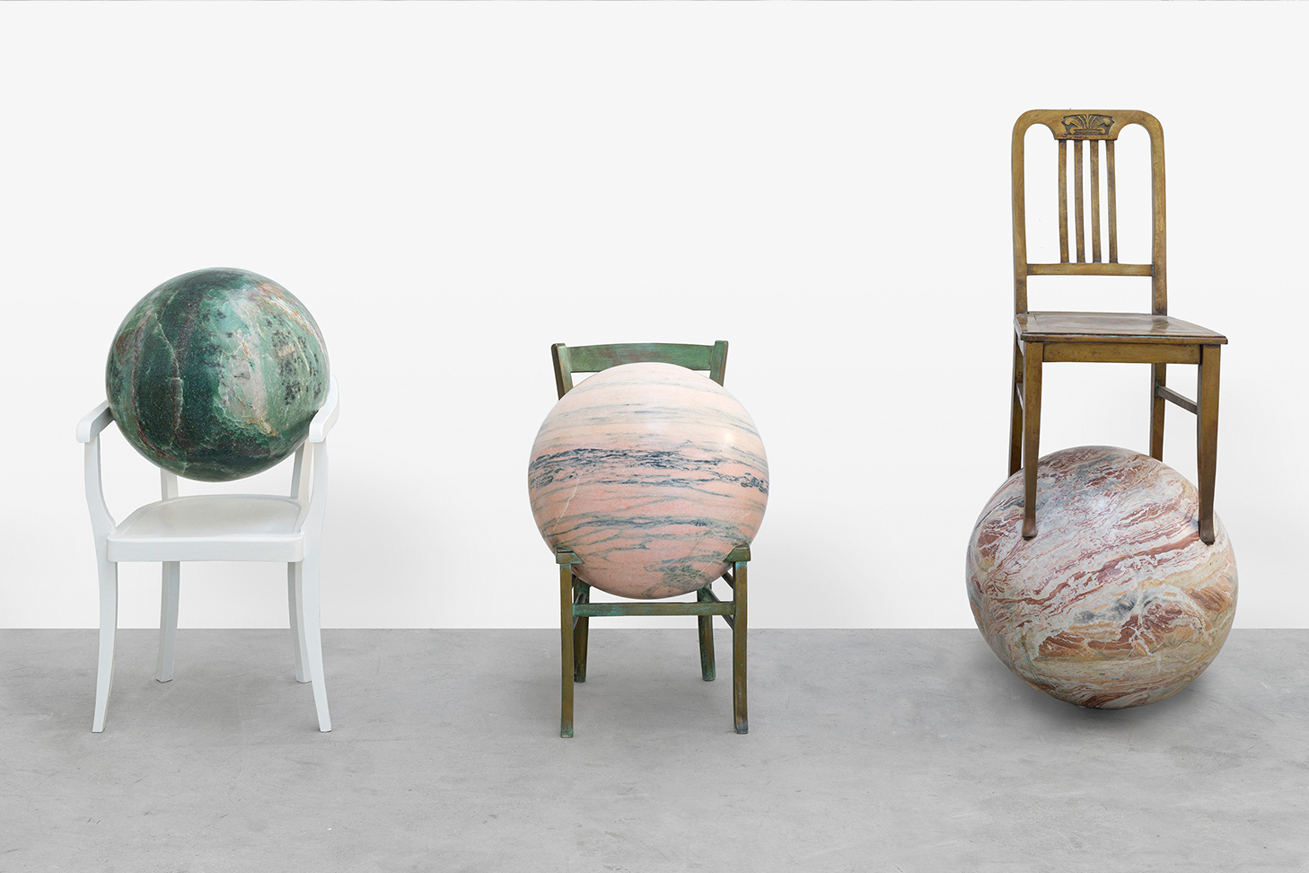 planets interacting with chairs in front of a white wall