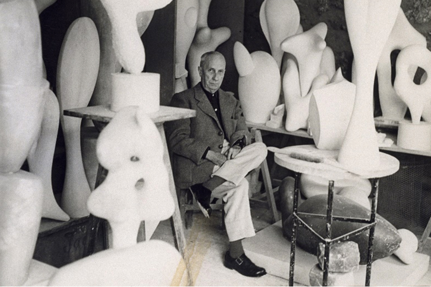 black and white photo of a man sitting among sculptures
