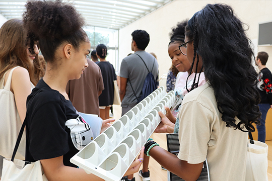 Three students hold a sample of a roof panel
