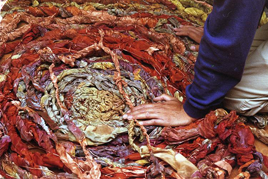 A hand touches a fabric sculpture that resembles intestines