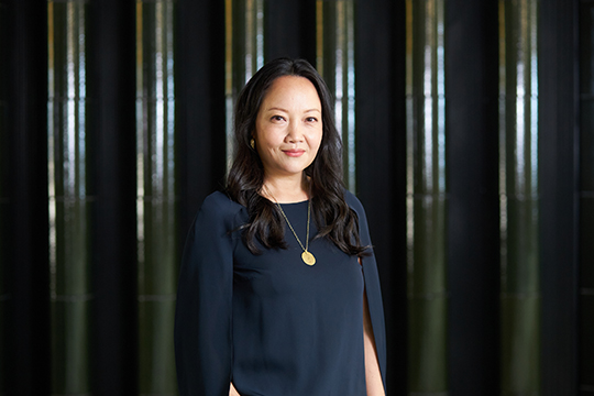 Mika Yoshitake smiles at the camera in front of a black background