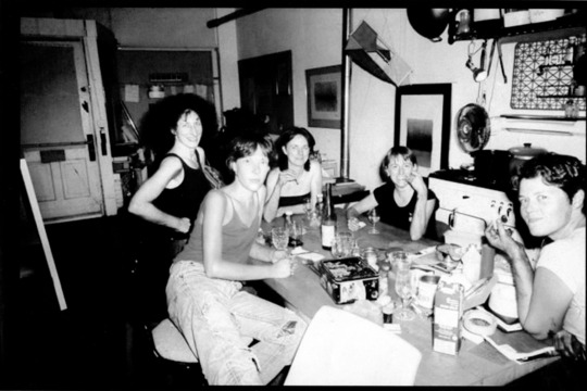 Black and white photo of five women gathered around a table