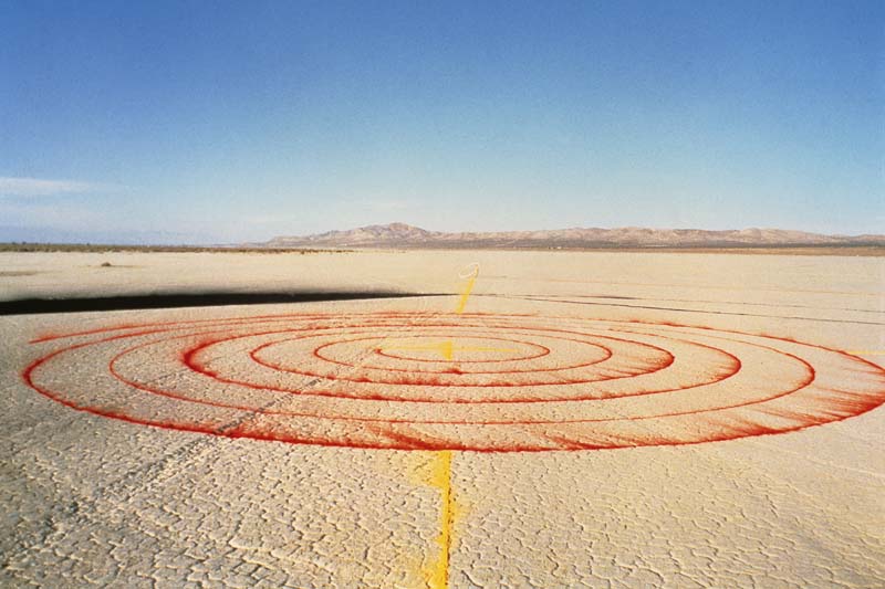 An image of the desert floor with a red spiral inscribed.