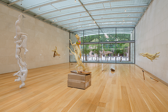 A group of plaster, rubber, and polyurethane sculptures depicting animal forms, suspended with wire and weighted by found objects, displayed in a white walled gallery space. 
