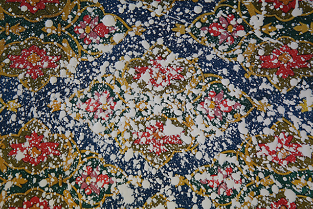 Video still of a project by Nida Bangash titled 'Projection', a Persian rug with white paint splattered over it