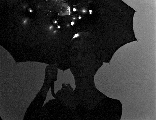 A dancer holding an umbrella is silhouetted in black and white A dancer holding an umbrella is silhouetted in black and white