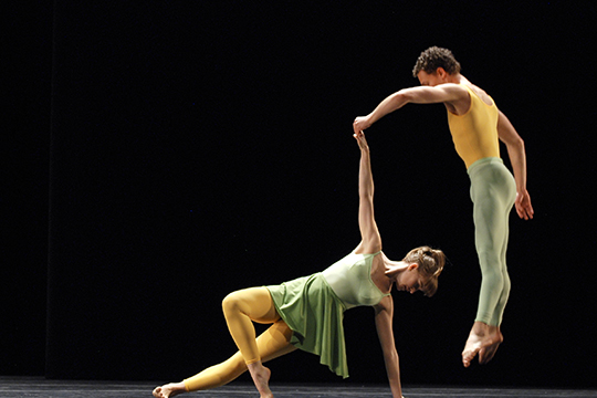Two dancers hold a pose against a dark background Two dancers hold a pose against a dark background