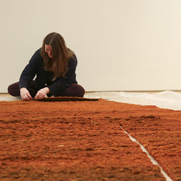 Conservator Claire Taggart works on a large fiber sculpture