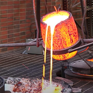 Image of a glowing crucible pouring molten bronze