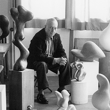 Jean Arp sitting among his sculptures 