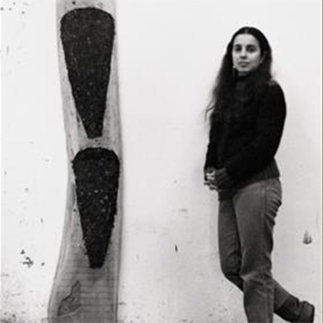 Artist Ana Mendieta standing next to a wooden sculpture